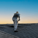 Roofing contractor scaling a roof as they lift up shingles.
