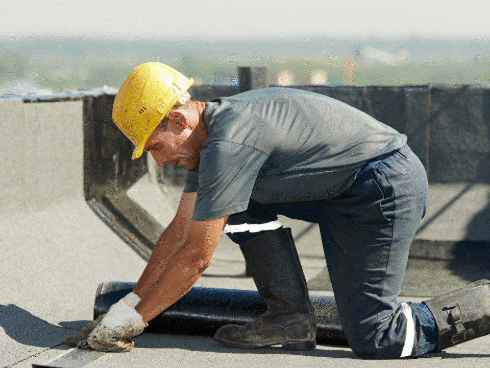 Roofer on a commercial roof replacing commerical roof damage in the summer.