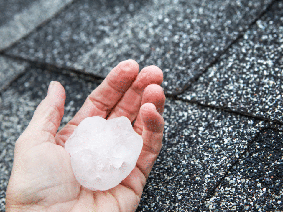 Person holding a hail core over a residential roof looking for hail damage.